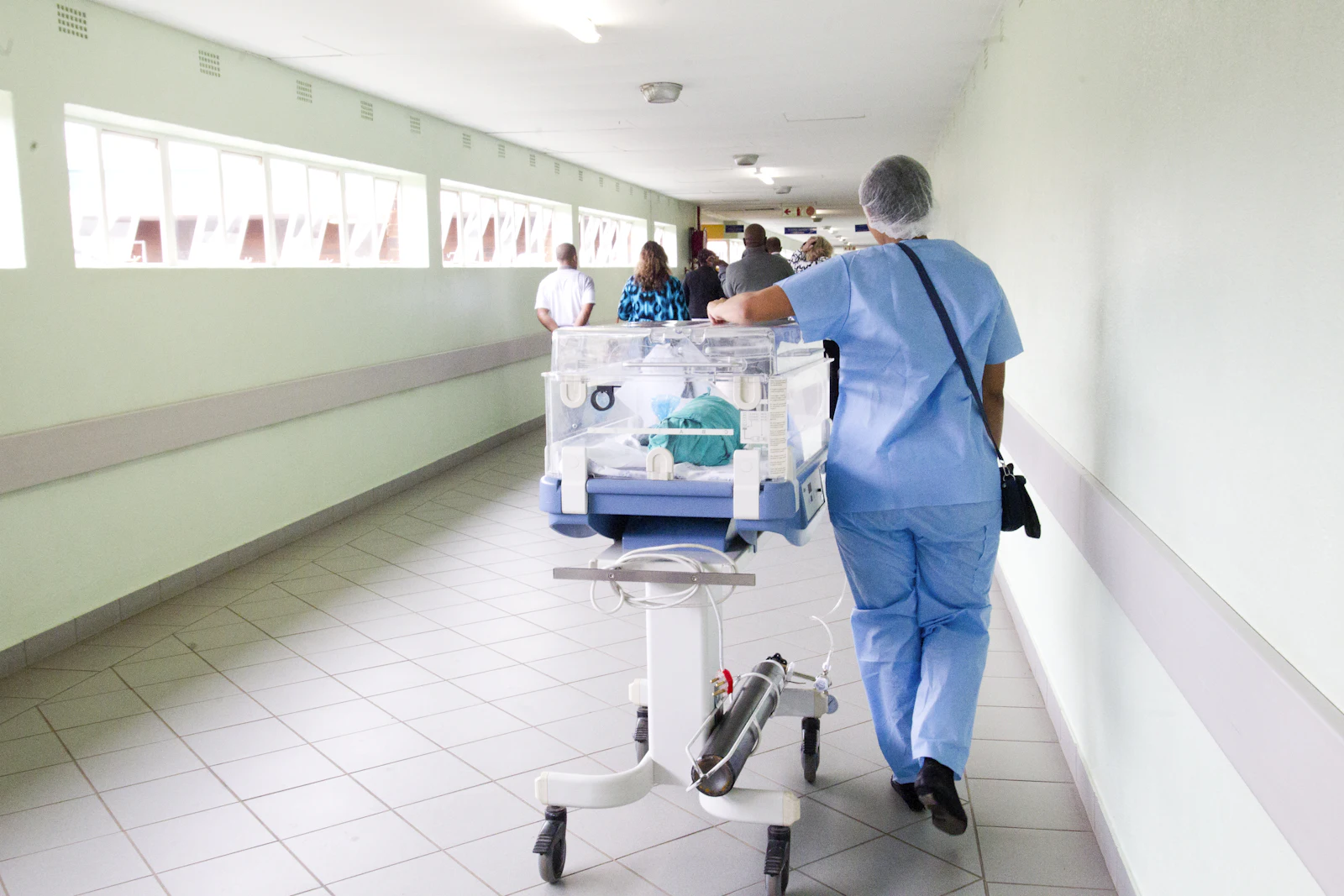 Hospital staff moving a patient along a bright corridor